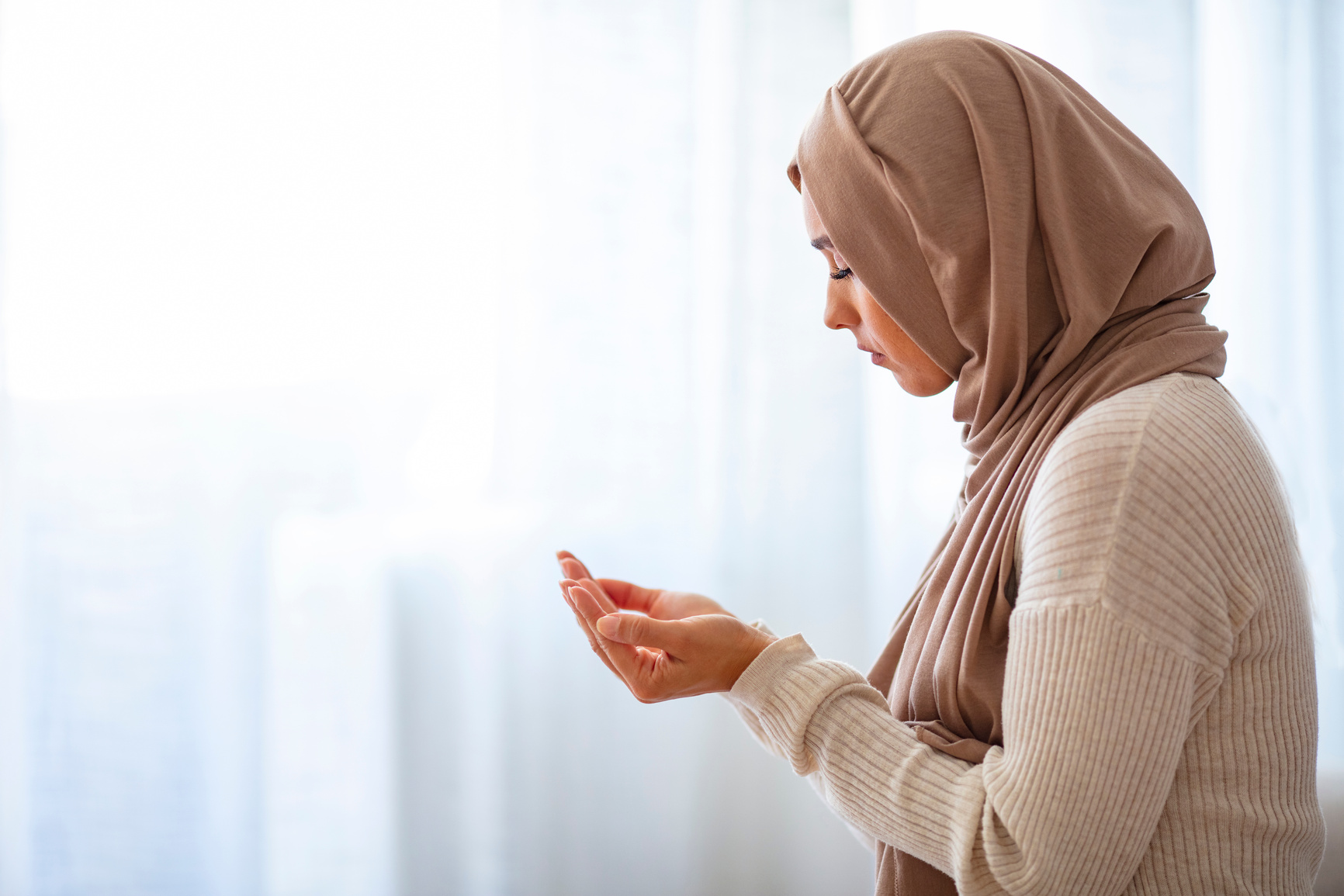 Young Muslim woman praying, indoors.
